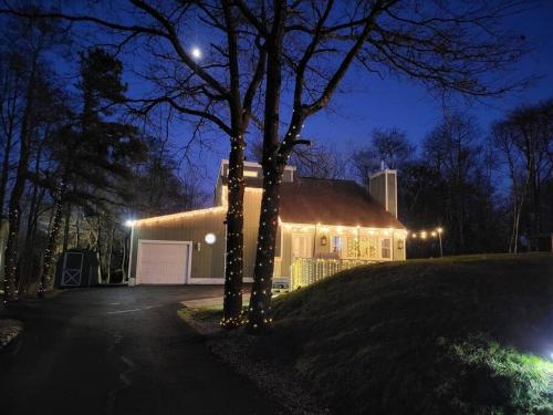 a house with lights on the side of it at night at Entire cottage, Firepit, BBQ, in & out pool access in Long Pond
