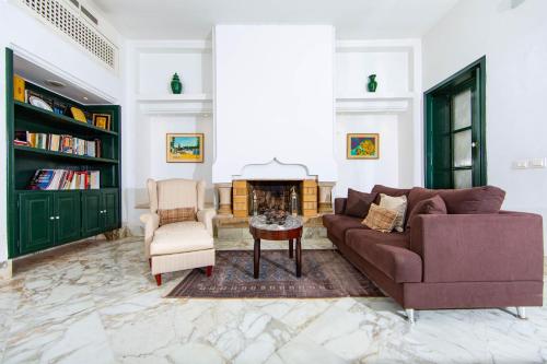 a living room with a couch and chairs and a fireplace at Arabesque House in La Marsa