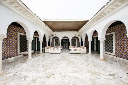 a large room with white columns and tiles on the walls at Arabesque House in La Marsa
