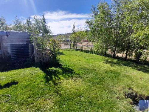 a yard with a fence and green grass and trees at Alquiler por día Gobernador Gregores in Gobernador Gregores
