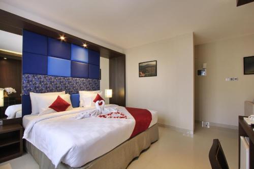 a bedroom with a large bed with a blue headboard at Ohana Hotel Kuta in Kuta