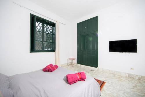 a bedroom with a bed with two pink pillows on it at Arabesque House in La Marsa