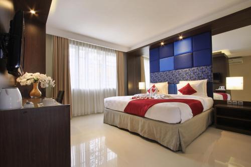 a hotel room with a large bed and a television at Ohana Hotel Kuta in Kuta