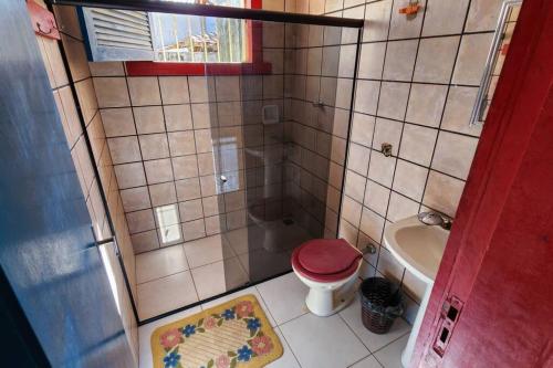 uma pequena casa de banho com um WC vermelho e um lavatório. em Casa Família Caldas em Nova Viçosa