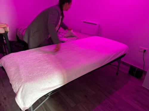 a woman standing next to a bed in a pink room at Jacuzzi privé arrivée autonome in Conflans-Sainte-Honorine