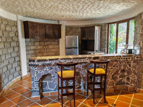 a kitchen with a counter with two stools and a fireplace at Mansion Tepotzotlan in Tepotzotlán