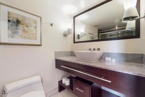 a bathroom with a sink and a mirror at The Regency at Beachwalk - Unit 93 in Honolulu