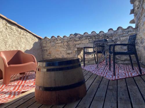 a wooden deck with a barrel and a chair at La Stévenière in Chandolas