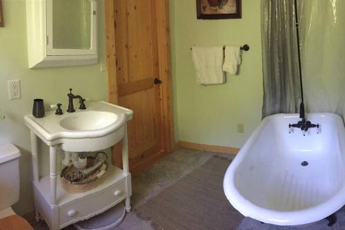 La salle de bains est pourvue d'un lavabo et d'une baignoire à côté des toilettes. dans l'établissement Peach Valley Retreat, à New Castle