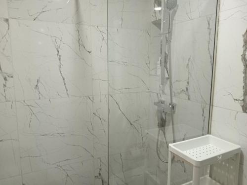 y baño con ducha y paredes de mármol blanco. en Studio neuf meublé donnant sur la forêt de nouaceur, en Nouaceur