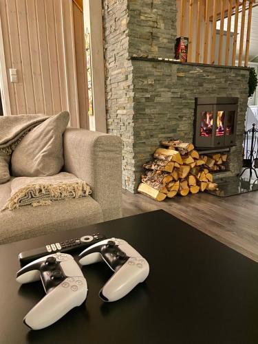 two video game controllers on a table in front of a fireplace at Riverfront house with 98 inch TV, ps5 & activities in Narvik