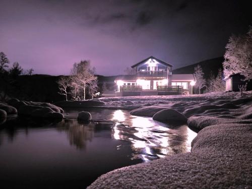 uma casa iluminada à noite ao lado de um rio em Idyllic valley getaway, perfect for families em Narvik