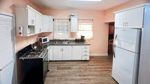 a kitchen with white cabinets and a white refrigerator at Lulu cottage in Basse Terre Town