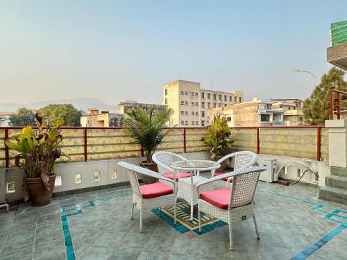 eine Terrasse mit einem Tisch und Stühlen auf dem Balkon in der Unterkunft Margalla Hills Residency Islamabad Guest House in Islamabad