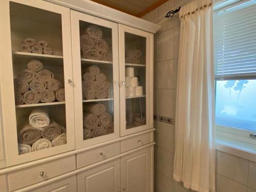a white cabinet with dishes in it in a bathroom at Riverfront house with 98 inch TV, ps5 & activities in Narvik
