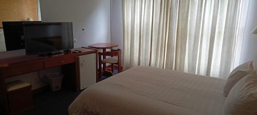 a hotel room with a bed and a flat screen tv at Hotel Viña del Sur in Tarija