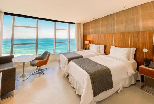 two beds in a hotel room with a view of the ocean at Hotel Nacional Rio de Janeiro in Rio de Janeiro