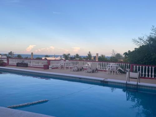 una piscina con mesas y sillas junto a una valla en Hotel Casa Cactus HCC en Chachalacas