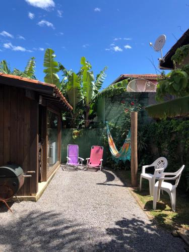 a patio with chairs and a hammock next to a house at Casinha Astral - Praia da Ferrugem in Garopaba