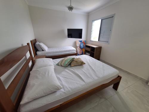 a bedroom with two beds and a television in it at Apto em Bertioga , pé na areia in Bertioga