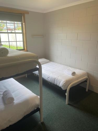 a room with three bunk beds and a window at Bridport Bay Inn in Bridport