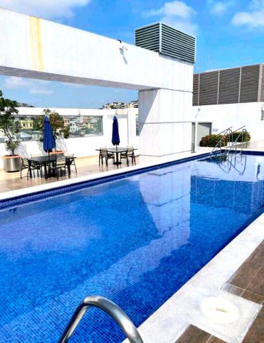 uma piscina com água azul em frente a um edifício em 2 habitaciónes vista al río 102 em Guayaquil