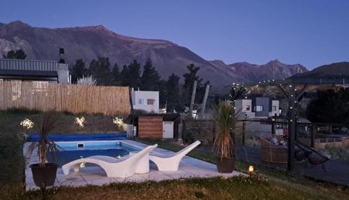a swimming pool with two white chairs next to it at Refugio del Pescador in Esquel