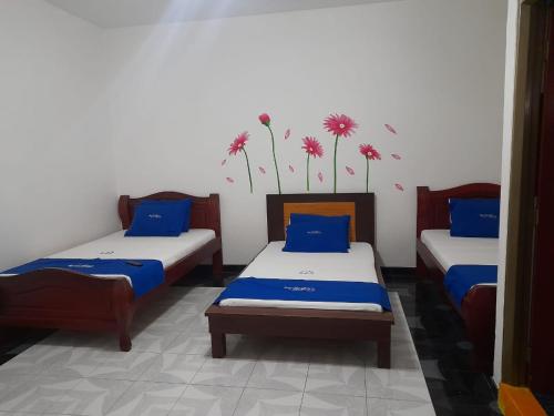 3 Betten in einem Zimmer mit Blumen an der Wand in der Unterkunft HOTEL PARAISO DE LAS GEMELAS in Montenegro