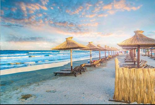 a beach with many chairs and umbrellas and the ocean at FERNWEH No 5 Boutique Hotel MAMAIA Nord in Mamaia Nord