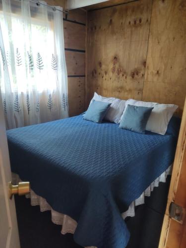1 dormitorio con cama azul y cabecero de madera en Cabaña Chaitén en Chaitén