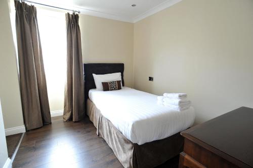 a bedroom with a bed with white sheets and a window at The Kings Arms Hotel in Berwick-Upon-Tweed