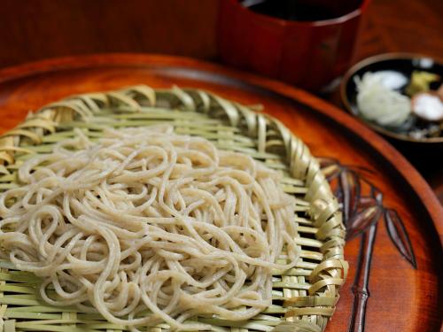 a plate of noodles on a wooden plate with a fork at 小さなホテルセラヴィ in Nagatoro