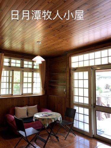 a living room with a table and chairs and windows at Cabin of Sun Moon Lake in Yuchi