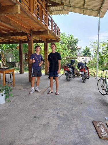 due uomini in piedi di fronte a un palazzo con le moto di Homestay tuấn bay du lịch cộng đồng a Yên Bái
