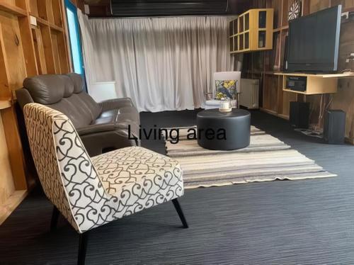 sala de estar con sofá y silla en Hosts on the Coast - Rocco's Retreat, en Kuaotunu