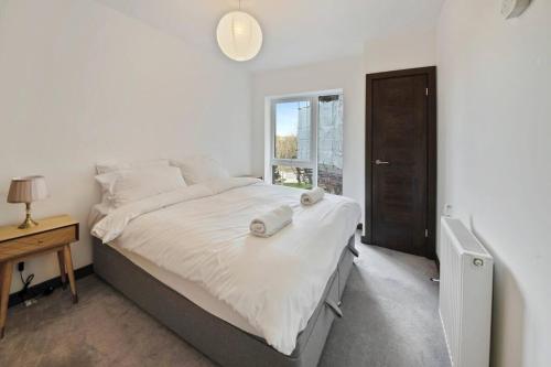 a white bedroom with a large bed and a window at The Fabulous Oasis In Kent in Kent
