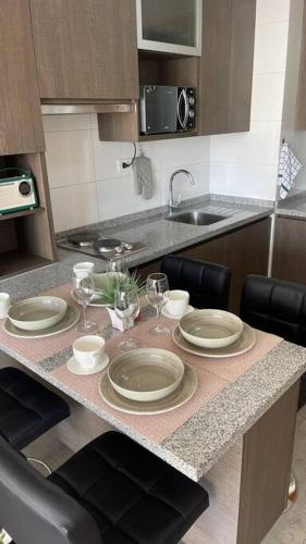 a kitchen with a table with plates and wine glasses at 8 Apartamento en Santiago en fente al Metro - Hipodromo de Chile y Estadio San Laura in Santiago