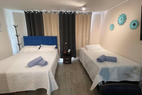 two beds in a room with blue pillows on them at Apartamento en Santiago. in Santiago