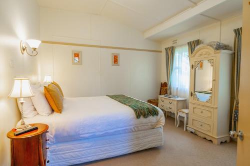 a bedroom with a bed and a dresser and a mirror at KUBBA ROONGA GUESTHOUSE - Boutique Luxury Spa Retreat & Gardens - Blue Mountains in Blackheath