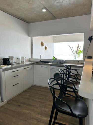 a kitchen with white cabinets and black chairs at Pension Irivai, Appartement RAVA 1 chambre bord de mer in Uturoa