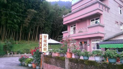 a pink house with potted plants in front of it at Cuiti B&B in Fenqihu