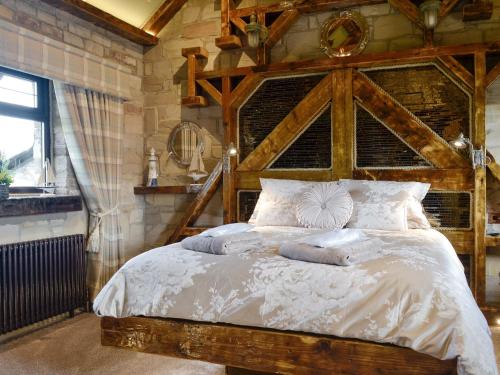 Schlafzimmer mit einem großen Bett mit einem Kopfteil aus Holz in der Unterkunft Tennox Boathouse - Ukc4438 in Kilbirnie