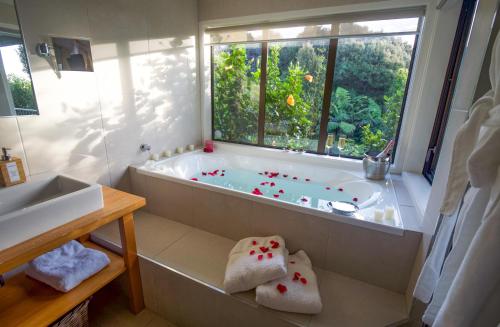 ein Bad mit einer Badewanne und einem Fenster in der Unterkunft The Retreat - Luxury Hillside villa at Te Ngaere Bay in Kaeo