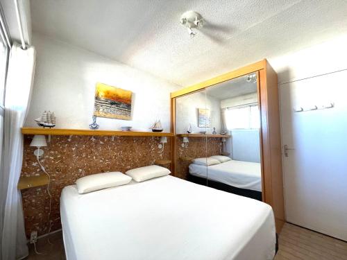 - une petite chambre avec 2 lits et un miroir dans l'établissement Appartement 2 pièces en bord de mer avec parking privé à Sète - FR-1-338-409, à Sète
