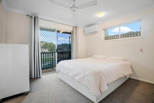 a white bedroom with a bed and a balcony at Luxurious Urban Eco Escape 3br in Brisbane