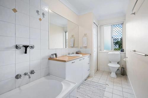 a white bathroom with a tub and a toilet at Luxurious Urban Eco Escape 3br in Brisbane