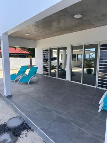 a patio with two blue chairs on it at Pension Irivai appartement PUATOU 1 chambre bord de mer in Uturoa