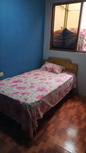 een slaapkamer met een bed met een roze sprei bij CASA JEI in Iquitos