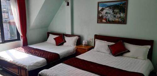 a bedroom with two beds with red and white pillows at Đại Loan Sapa Hotel in Sapa