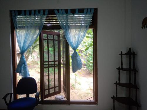 uma janela com cortinas azuis e uma cadeira num quarto em KGIS em Gelioya